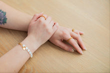 Load image into Gallery viewer, Close-up of a person's wrist with bracelets and rings on a wooden surface
