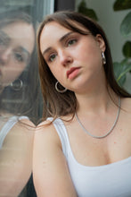 Load image into Gallery viewer, Woman wearing a white tank top and silver hoop earrings with a blurred background

