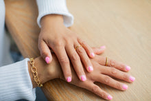 Load image into Gallery viewer, Two hands with gold rings and bracelets on a wooden surface
